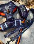 Dog Harness and Leash Set - Black & Gray camo dog harness with Orange Accents and Matching Dog Leash - outdoors laying on a log with fall leaves on the ground - Wag Trendz