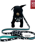 No Pull Dog Harness - black stuffed dog model wearing black adjustable harness - white paint splatter and teal accents and matching dog leash and dog poop bag holder attached- against a solid white background - Wag Trendz