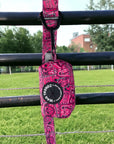 Dog Poo Bag Holder - Bandana Boujee - Hot Pink with black zipper and black rubber logo dispenser on front hanging on a matching leash outdoors on a black fence with green grass in background - Wag Trendz