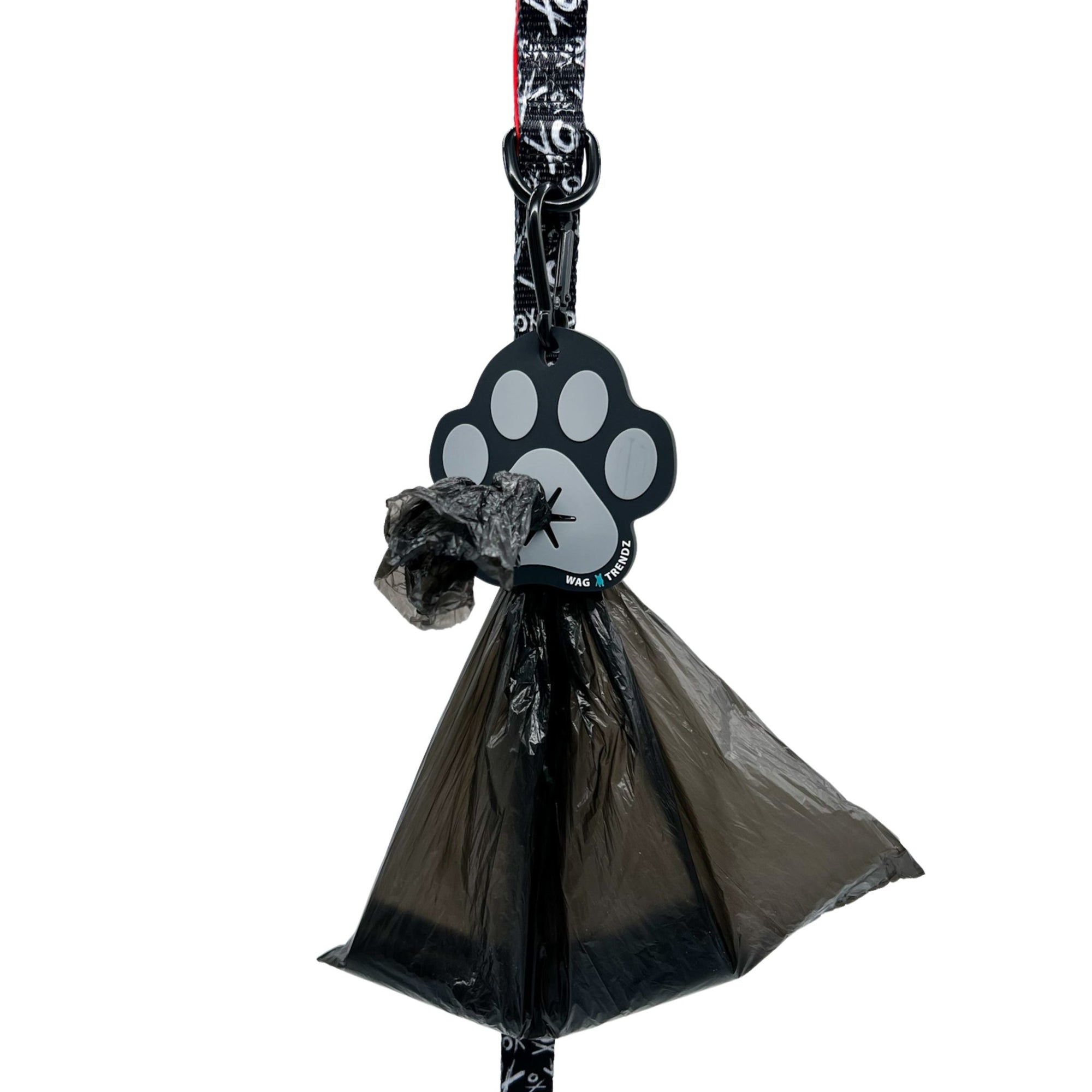 Poop Buddy - black and gray resin dog paw - hanging on a black &amp; white XO dog leash with red accents and black plastic bag carrying poop pushed through hole - against white background - Wag Trendz